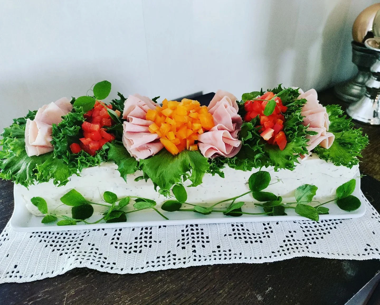 Kinkkuvoileipäkakku koristeltuna salaatilla, paprikalla ja kinkkuruusukkeilla